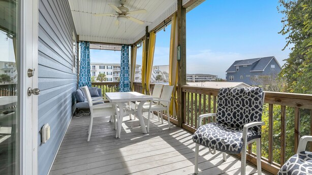 A covered porch with a table and chairs, a ceiling fan, and a view of a house. - Bonne Mer: Three bedroom, two bathroom house in Oak Island close to shopping and (Oak Island)