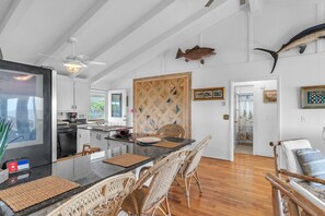 A spacious kitchen with a large island, wooden chairs, and a ceiling fan.