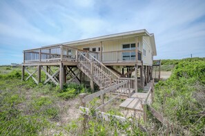 Une maison en bois à deux étages, dotée d’une terrasse et d’un escalier.