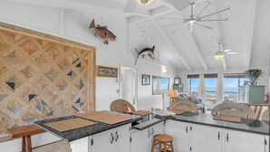 Una cocina amplia con una isla grande, armarios blancos y vistas al exterior.