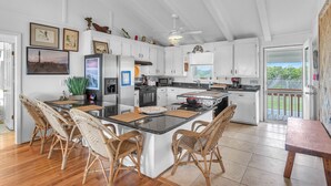Una cocina amplia con una isla grande, muebles blancos y vistas al exterior.