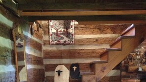 A wooden staircase leading to a loft area with a quilted bed and a decorative mirror.