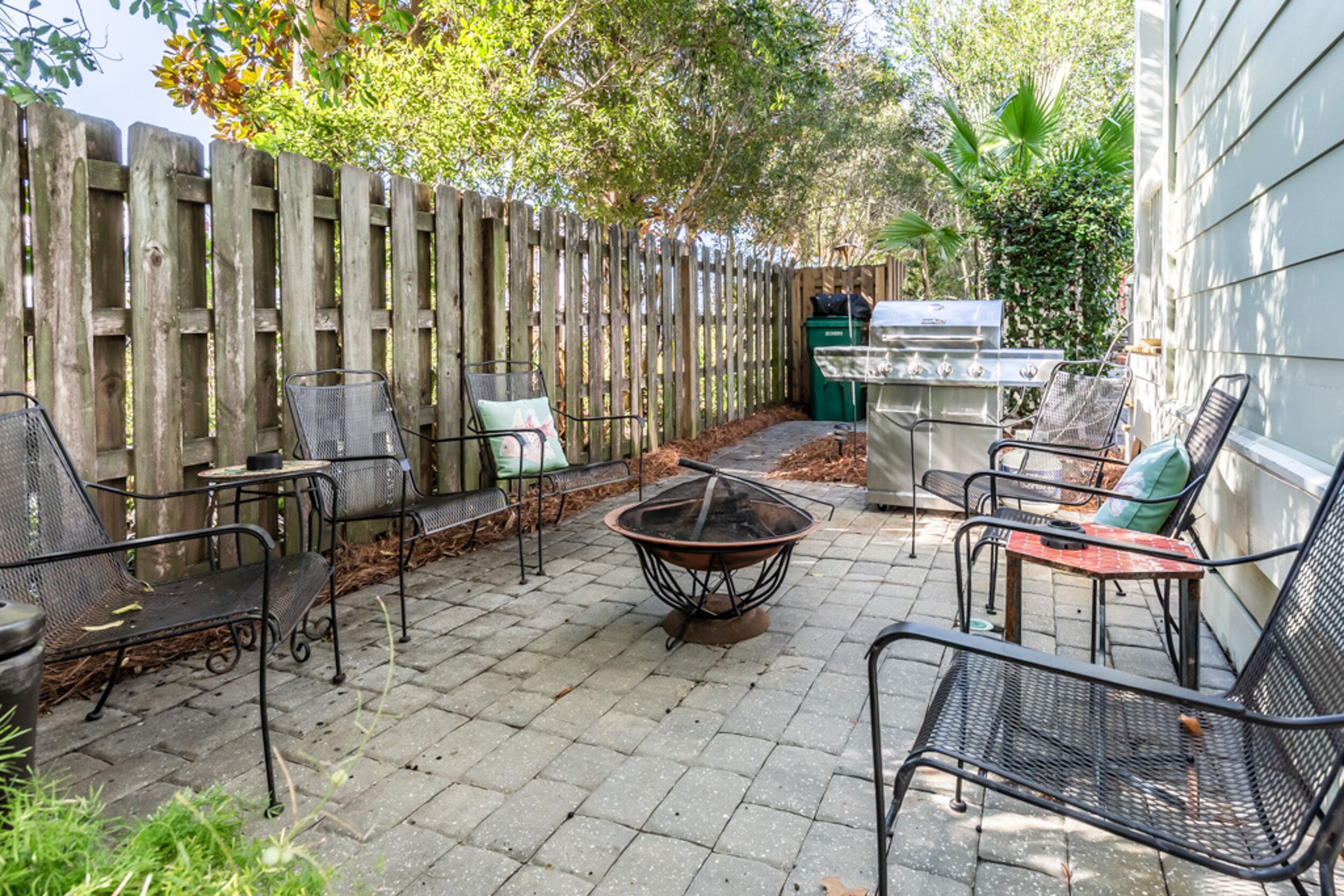 Une terrasse extérieure avec des chaises en métal, un foyer et un espace barbecue.