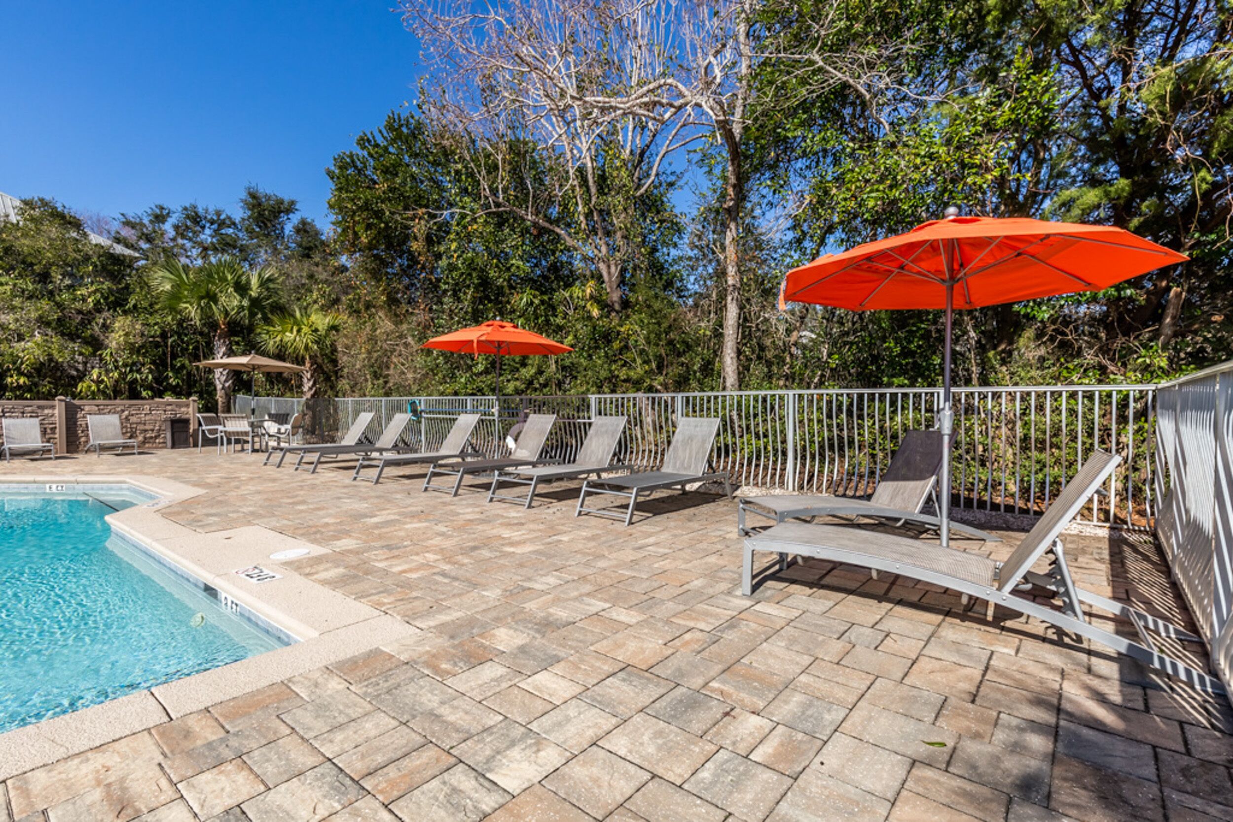 A poolside area with lounge chairs and two red umbrellas.