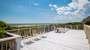 A wooden deck with white chairs and a view of the beach. - Beechouse: Oceanfront Condo with Great Views, Community Pool, Near Golf Course (Caswell Beach)