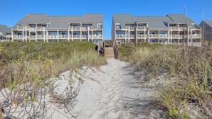 A beachfront hotel with a sandy path leading to the entrance. - Beechouse: Oceanfront Condo with Great Views, Community Pool, Near Golf Course (Caswell Beach)