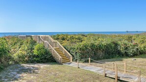A wooden staircase leading down to a beach, surrounded by dense vegetation. - Beechouse: Oceanfront Condo with Great Views, Community Pool, Near Golf Course (Caswell Beach)
