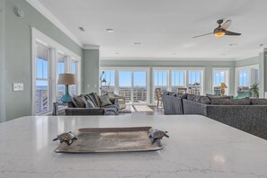 A spacious living area with a large island, a ceiling fan, and a view of the outdoors. - Turtle Soup: Oceanfront home in East Beach with plenty of ocean leading windows (Oak Island)