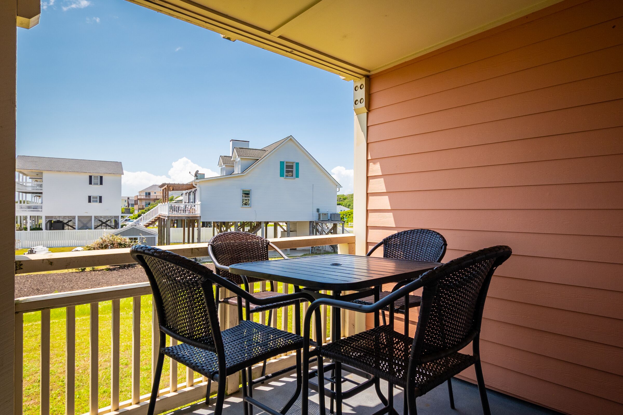 Ein Balkon mit Tisch und Stühlen mit Blick auf eine Wohngegend, mit Häusern und einem weißen Zaun.
