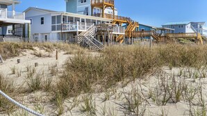 A beachfront property with multiple levels, wooden walkways, and a sandy beach area. - Blu Malibu: 5 Bed/3 Bath Oceanfront Home, Walking Distance to Davis Canal. (Oak Island)