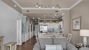 A modern kitchen with white cabinets, stainless steel appliances, and pendant lighting.
