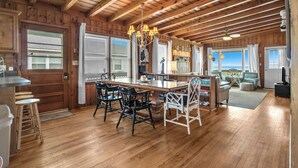 Une cabane en bois spacieuse comprenant un coin repas, une cuisine et un salon.