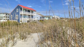 Une propriété située en bord de mer, avec une maison à deux étages dotée d’un toit rouge et d’un balcon.