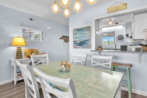 A dining area with a table, chairs, a lamp, and a painting on the wall.