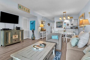 A living room with a television, a coffee table, a sofa, and a dining area with a table and chairs.