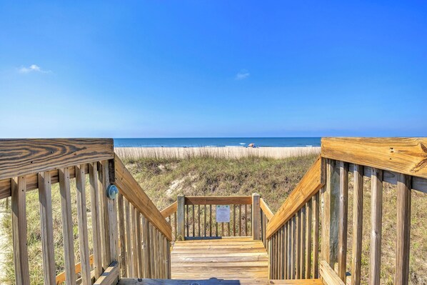 A wooden boardwalk leading to a beach with clear skies.