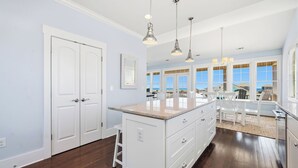 Una cocina con una isla central, armarios blancos e iluminación colgante.