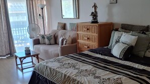 Une chambre à coucher avec un grand lit, une commode en bois, un canapé et un ventilateur.