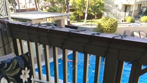 Un balcon doté de meubles en osier et offrant une vue sur une piscine.