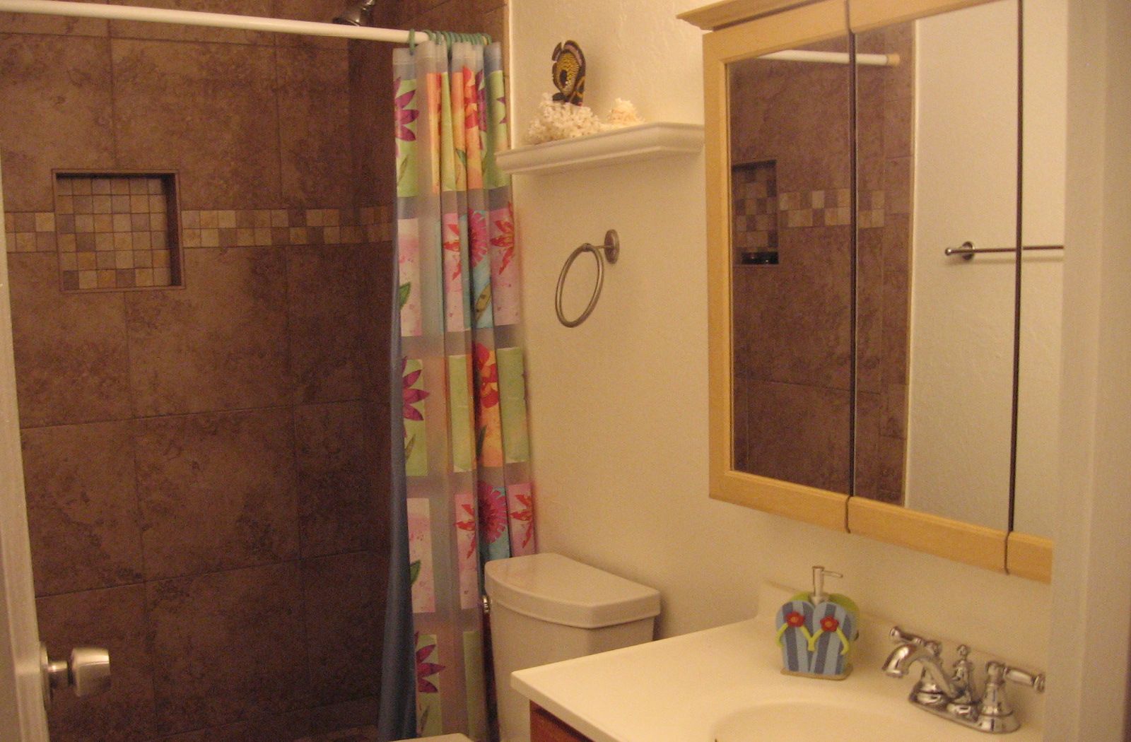 Un baño con ducha, inodoro, lavamanos y espejo.