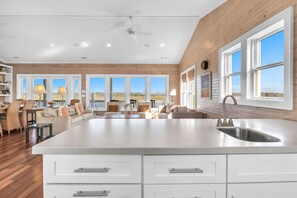 Una cocina amplia con una isla grande, armarios blancos y un lavamanos de acero inoxidable.