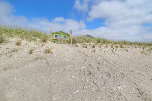Een groene woning op een zandduin met een heldere lucht.
