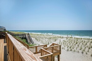 Un paseo marítimo de madera que conduce a una playa, con vista despejada al océano.