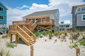 Una propiedad frente a la playa con una terraza de madera, varios niveles y una zona de arena.