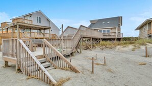 Una propiedad frente a la playa con terrazas de madera y escaleras que dan a la arena.