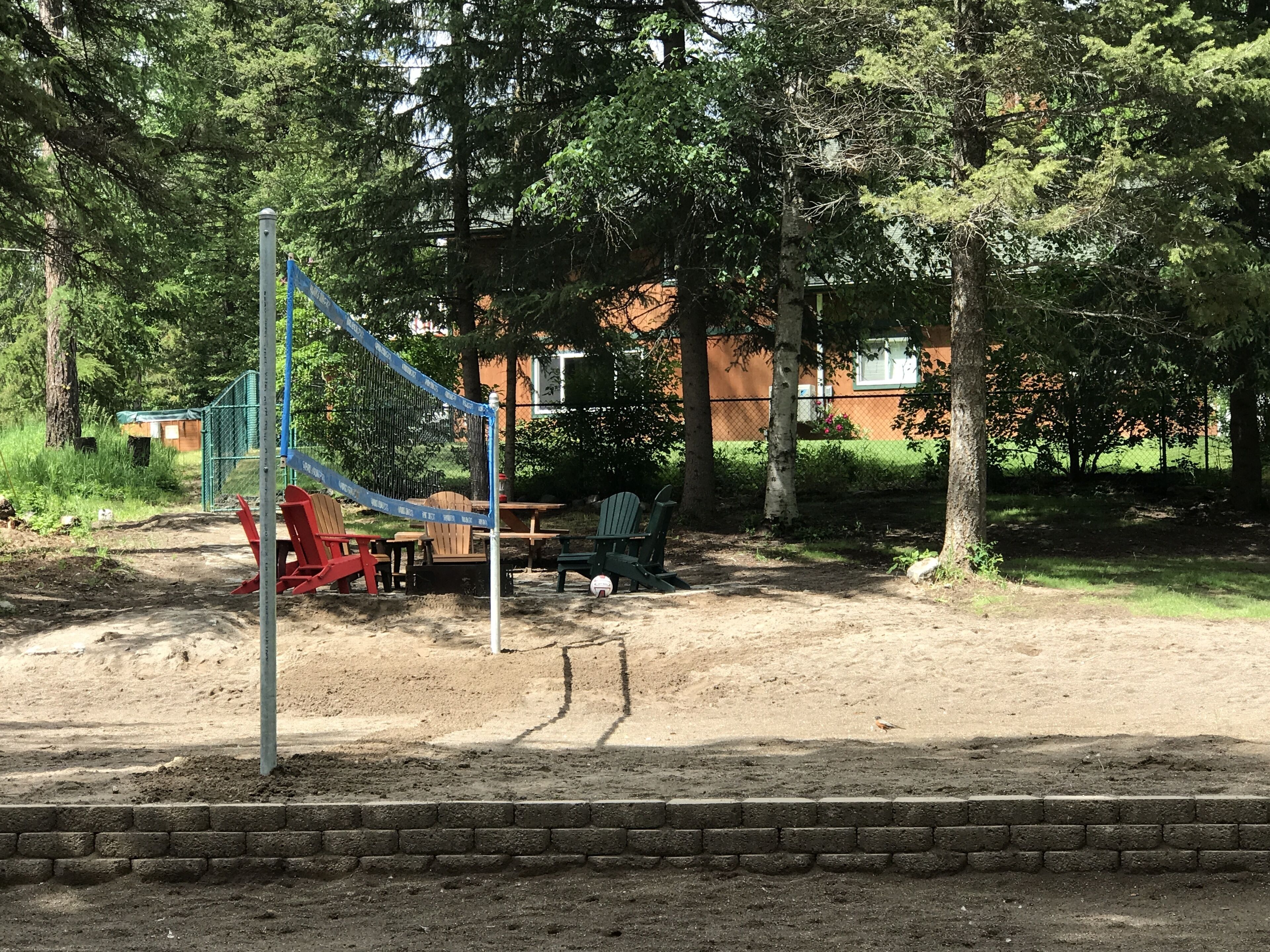A volleyball net, outdoor seating, and trees in a park setting.
