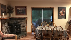 A cozy living room with a stone fireplace, wooden dining table, and chairs. - "Serene, tranquil home near Glacier National Park, great for 2 Families!" (Columbia Falls)