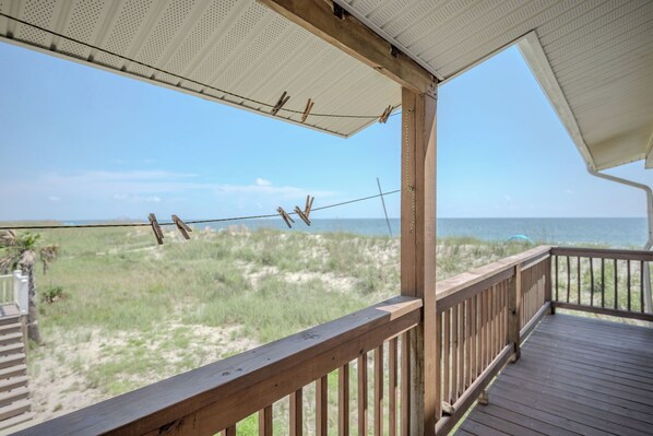 A wooden deck with a view of the beach and ocean. - Beach Bums: Bright and Inviting Oceanfront Home (Oak Island)