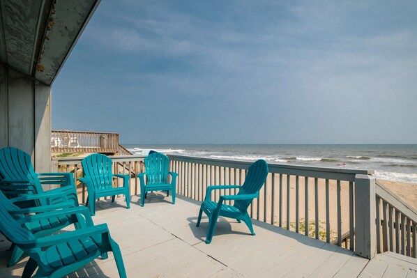 Relax on the balcony with ocean views, surrounded by Adirondack chairs.