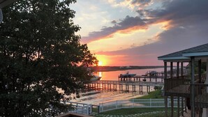 A waterfront view with a sunset, docked boats, and a gazebo.