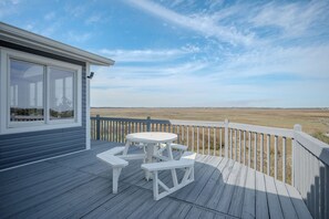 A deck with a picnic table and benches, overlooking a grassy field. - Late for the Sky: Ocean and Waterway Views, Near Beach Access (Caswell Beach)
