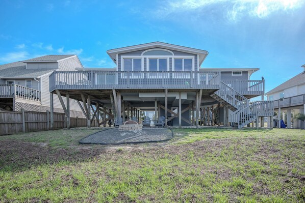 A two-story house with a covered porch, a staircase, and a fenced yard. - Late for the Sky: Ocean and Waterway Views, Near Beach Access (Caswell Beach)