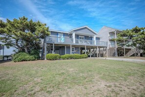 A two-story building with a covered porch and a fenced yard. - Late for the Sky: Ocean and Waterway Views, Near Beach Access (Caswell Beach)