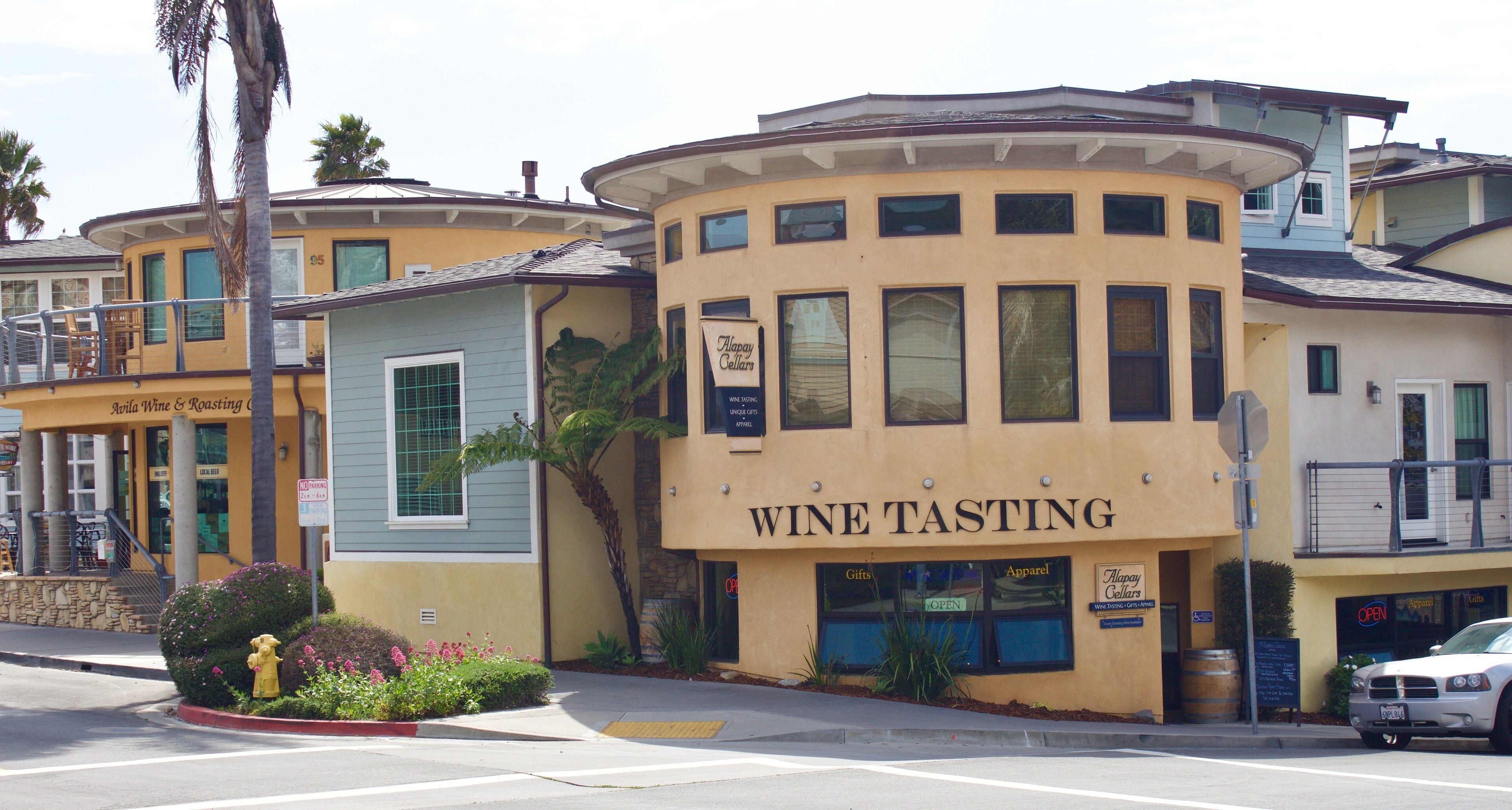 A building with a wine tasting establishment on the ground floor, featuring large windows and a curved corner design.
