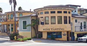 A building with a wine tasting establishment on the ground floor, featuring large windows and a curved corner design. - Bikini Bungalow - Large condo, Steps from Beach + Parking, Family (Avila Beach)