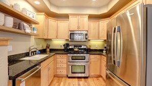 A modern kitchen with wooden cabinets, stainless steel appliances, a granite countertop, and a built-in oven. - Bikini Bungalow - Large condo, Steps from Beach + Parking, Family (Avila Beach)