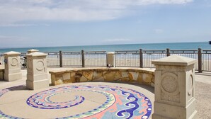 A coastal promenade with a circular mosaic, stone benches, and a metal railing overlooking the sea. - Bikini Bungalow - Large condo, Steps from Beach + Parking, Family (Avila Beach)