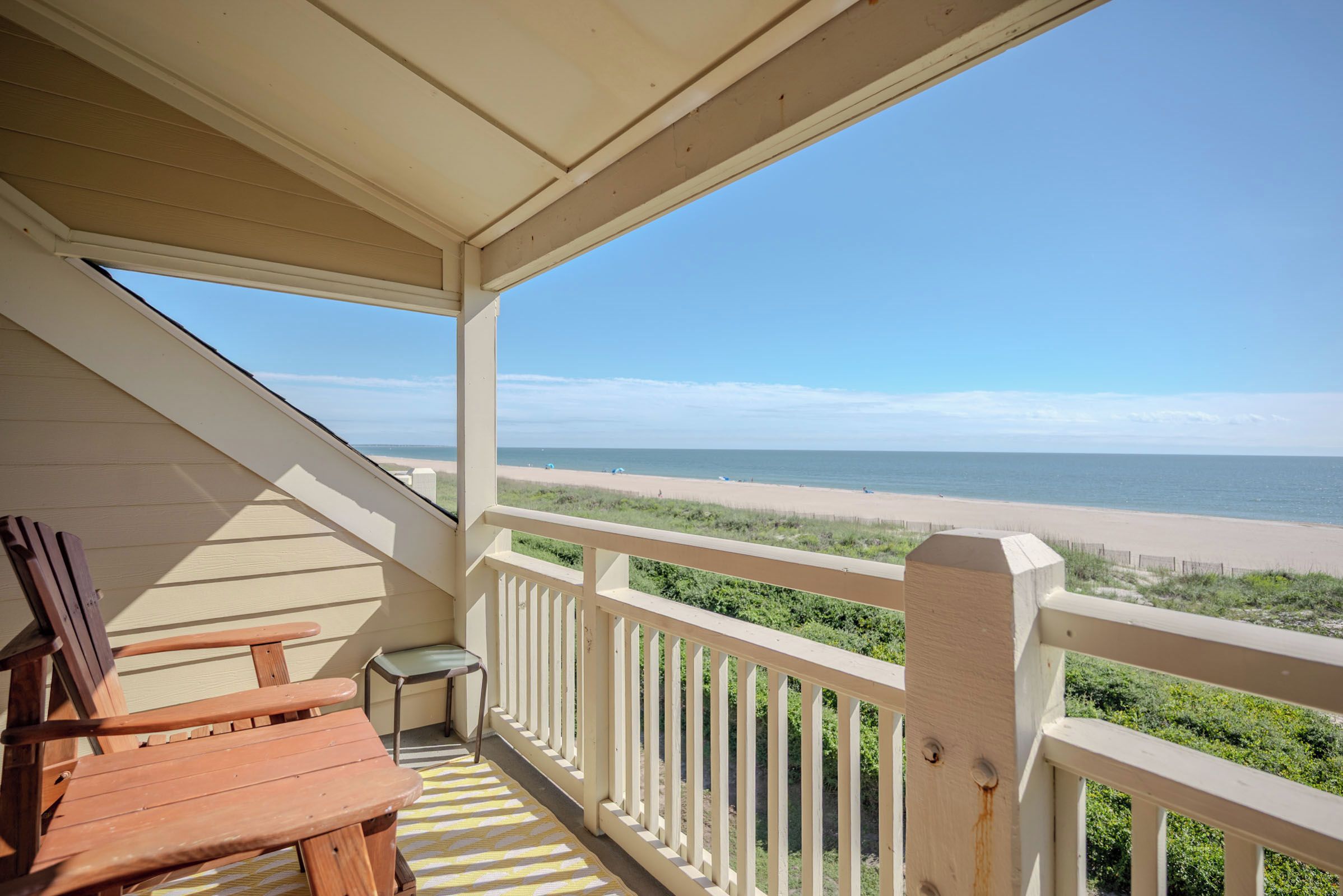 A covered balcony with a view of a beach and ocean.