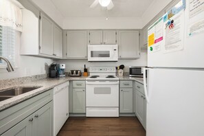 A kitchen with white cabinets, a microwave, a stove, and a refrigerator.