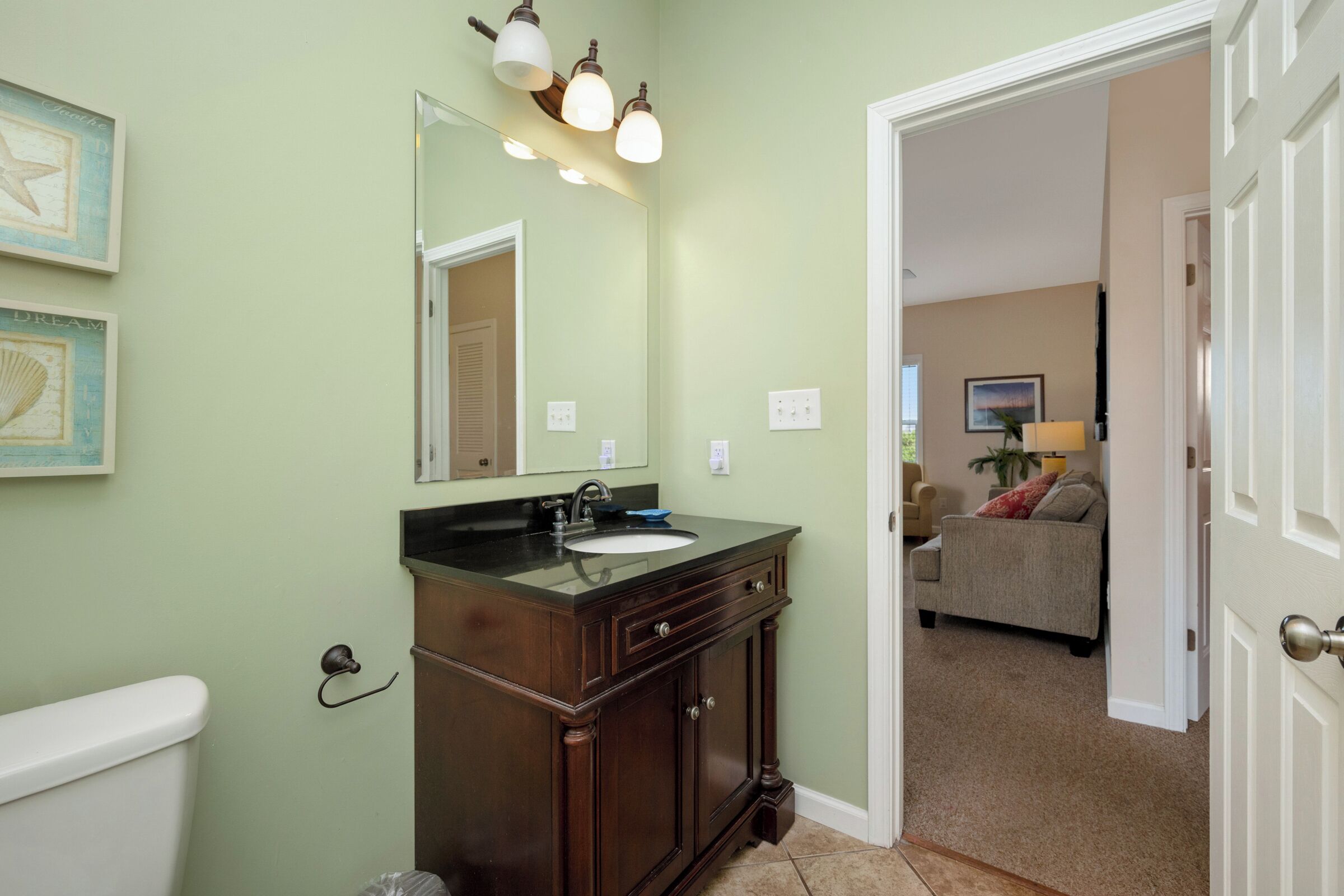 A bathroom with a dark wood vanity, a white toilet, and a mirror above the sink.