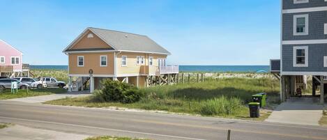 A coastal road with houses, a beach, and a clear sky.