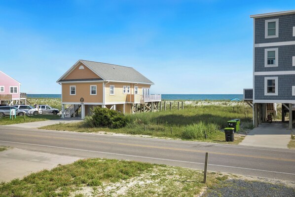 A coastal road with houses, a beach, and a clear sky.