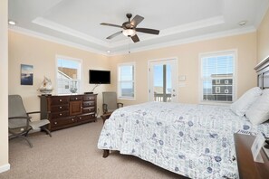 A bedroom with a bed, dresser, TV, and a ceiling fan. - This Is It: Great 2nd Row House with Views! (Oak Island)