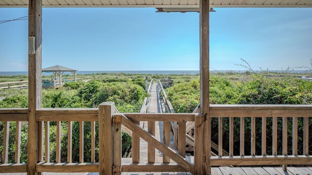 A wooden deck with a view of a boardwalk leading to a gazebo by the water. - Linger Longer: Oceanfront with Great Views of Lighthouse (Caswell Beach)