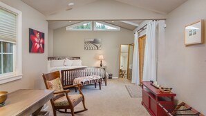 A bedroom with a bed, bedside table, lamp, rocking chair, and a red console table with a mirror. - Pleasure Point Oasis ~ Family and dog-friendly yard ~ Off-street parking (Santa Cruz)