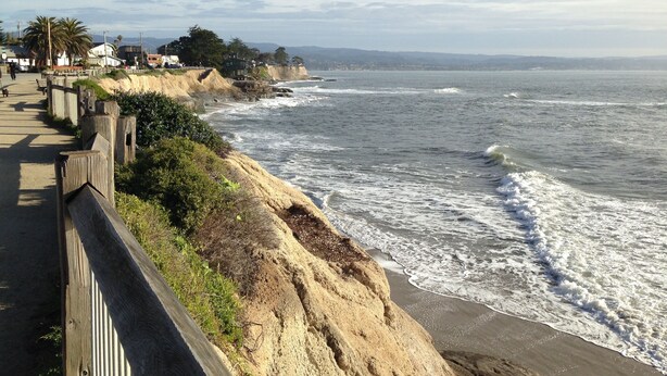 A coastal walkway with a wooden railing, leading to a sandy beach with waves crashing onto the shore. - Pleasure Point Oasis ~ Family and dog-friendly yard ~ Off-street parking (Santa Cruz)